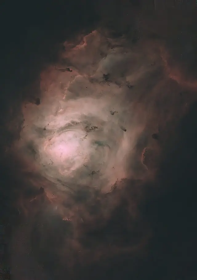 The Lagoon Nebula (M8) in Sagittarius, pink hydrogen gas crossed by dark dust lanes